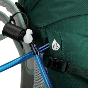 Close-up detail of green outdoor hiking backpack hydration system tube port and durable fabric.