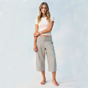 Detailed view of casual loose cropped pants with studded folded waistband and white top on model.