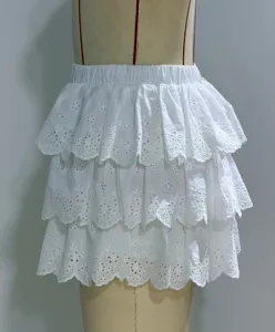 White eyelet tiered ruffle mini skirt detail view, showcasing delicate floral embroidery.