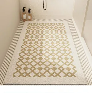 Crèmekleurige badkamermat van lusdraden met elegant goudkleurig geometrisch ruitpatroon.