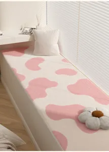 Detailweergave van zacht roze en wit koeienprint pluche erkerraammat met gezellige kussens.