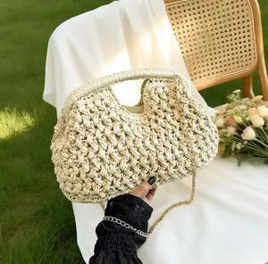Detail shot of the straw woven handbag showing exquisite texture, metal chain, and frame design.