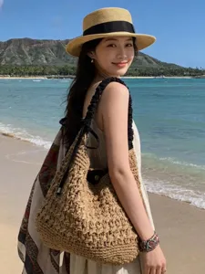 Beach straw shoulder bag detail shot, featuring hollow-out knit and black bow strap.