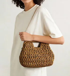 Detail view of stylish woven straw shoulder bag with metallic chain, perfect for summer beach.