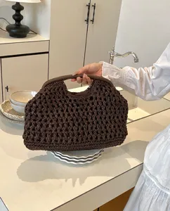 Detail view of a brown paper straw woven clutch bag, retro casual shell shaped handbag for women.