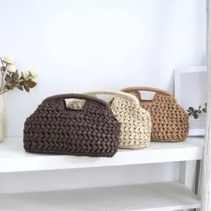 Detailed view of woven paper rope straw clutch bags in three colors on a clean white shelf display.