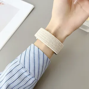 Detailopname van beige gevlochten nylon vervangende smartwatchband om de pols, comfortabel.