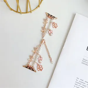 Bracelet de montre en métal doré rose avec perles et pendentifs trèfle, accessoire élégant.