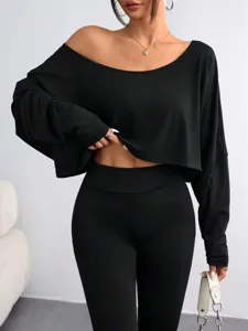 Detail shot of black off-the-shoulder long sleeve crop top and pants set for women.