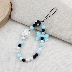 Detailed view of sweet blue and black beaded phone strap, bow charm and love heart accent.