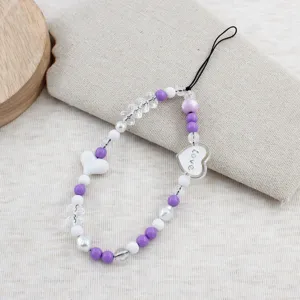 Purple and white beaded phone charm strap detail showing crystal beads and heart pendant.