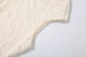 Close-up detail van dames bloemen holle kant mouwloze jurk stof in lichte crème beige kleur.