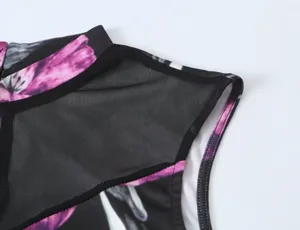 Detailopname van de schouder van een mouwloze damesjurk, zwarte mesh met roze bloemenprint erop.