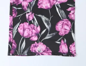 Detailopname van zwarte elastische gebreide stof met paarse bloemenprint en nette zoom.