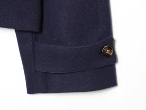 Detailed view of the dark blue woolen coat cuff with stylish button and strap trim.