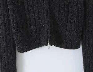 Close-up detail of dark grey cable knit cardigan featuring textured knit and metal zipper.
