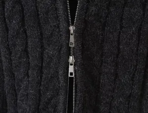 Close up of black cable knit cardigan with metal double zipper detail, cozy autumn apparel.