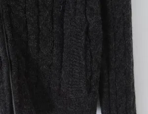 Close-up knit texture detail of womens dark grey cable knit cardigan with zipper design.