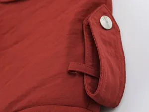 Detailed view of red women apparel with metallic snap button and pocket design. Premium quality.