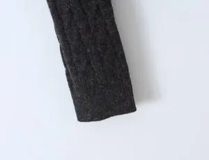 Close-up detail of dark grey cable knit sweater sleeve, soft textured fabric design.