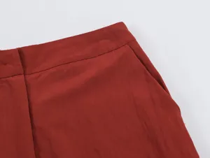 Detail view of women's casual trousers waistband and side pocket in solid rust red.