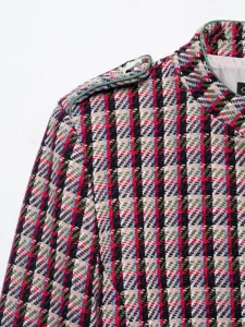 Detailed view of women's tweed textured jacket featuring colorful woven pattern and green piping.