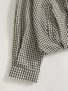 Detailed shot of black and white checkered women bomber jacket sleeve texture and pocket.