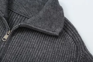 Close-up detail of dark gray ribbed knit cardigan collar and metal zipper texture design.