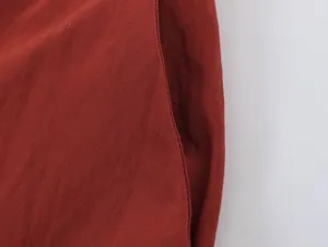 Close-up detail of solid red fabric texture and neat stitching seam for apparel styling.