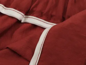 Detailed view of red casual clothing fabric with white piping trim, soft texture.