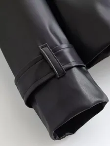 Close-up detail of women's black PU leather jacket sleeve cuff with stylish strap buckle.