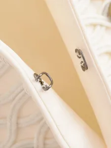 Close-up of metal hook clasp and braided trim on a elegant women woven jacket detail.