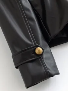 Detailed view of women's black faux leather jacket sleeve with stylish brass button cuff strap.