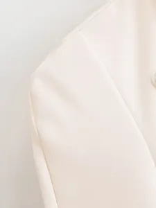 Close-up detail of women cream blazer shoulder, tailored fit, elegant fabric, fashion apparel.