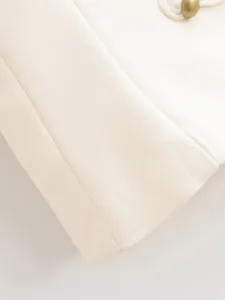 Detailed shot of women's apparel fabric with decorative white cord and metallic button accent.