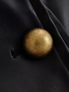 Black leather jacket button detail shot, vintage metallic dome button, premium texture.