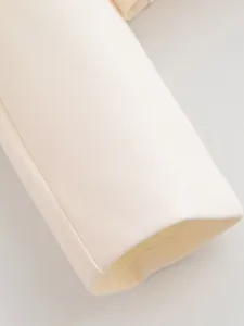 Close-up view of elegant beige blazer sleeve cuff, showing fine fabric texture and neat stitching.