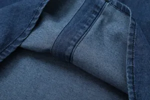 Denim fabric close-up detail showcasing fine texture, contrast stitching and fold quality.