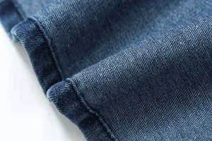 Close-up detail of blue denim fabric featuring fine stitching and textured weave pattern.