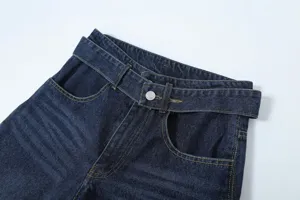 Dark blue denim pants waist detail with stylish cutout crossover belt and yellow stitching.