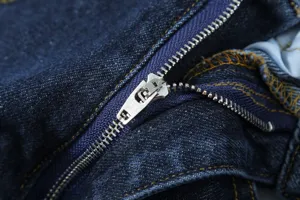 Close-up of dark blue denim jeans zipper with neat yellow stitching, high quality detail.