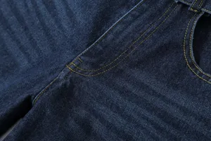 Close-up detail shot of dark blue denim fabric featuring contrast yellow topstitching.