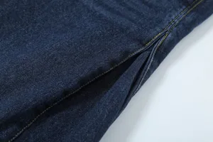 Dark blue denim clothing detail shot showcasing contrast yellow stitching and fine craftsmanship.