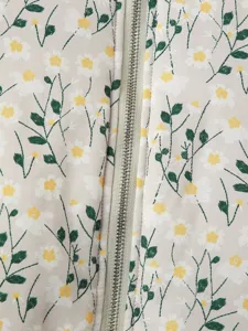 Close-up of women's floral jacket fabric detail featuring daisy pattern and center zipper.