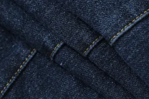 Detailed dark blue denim fabric texture with contrast yellow stitching close up view.