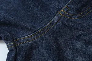 Dark blue denim fabric close-up showing durable double yellow stitching detail and texture.