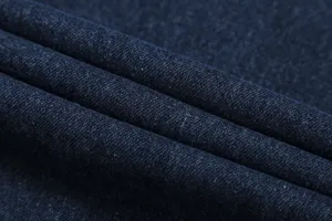 Detailed close-up shot of dark blue denim fabric showing premium twill texture and soft folds.