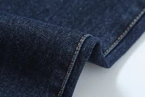 Denim fabric texture detail close-up showing fine weaving and yellow stitching lines.