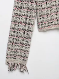Close-up detail of womens tweed knit cardigan sleeve with stylish fringe and multicolored texture.