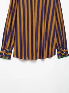 Close-up view of the striped long-sleeve shirt with decorative ruffled buttoned cuffs.